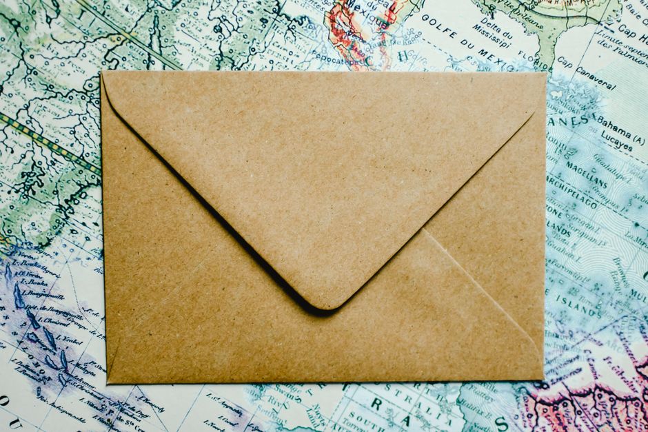 A brown envelope placed on a vintage world map, offering an adventurous theme.